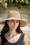 Woman wearing a straw hat with sunlight casting shadows on her face, outdoors.