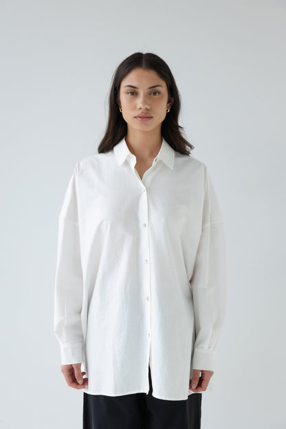 Woman wearing a white shirt against a plain background