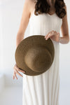 Woman holding a brown straw hat against a white background