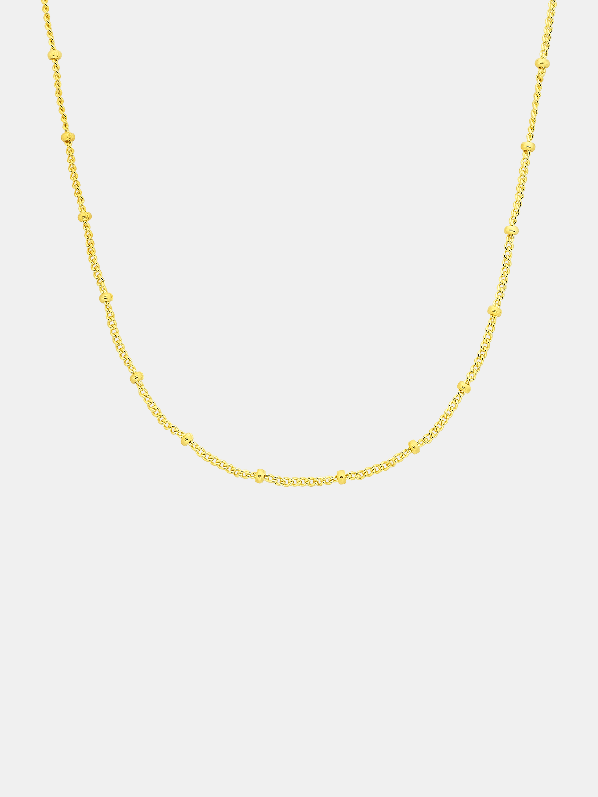 Gold chain necklace on a light gray background