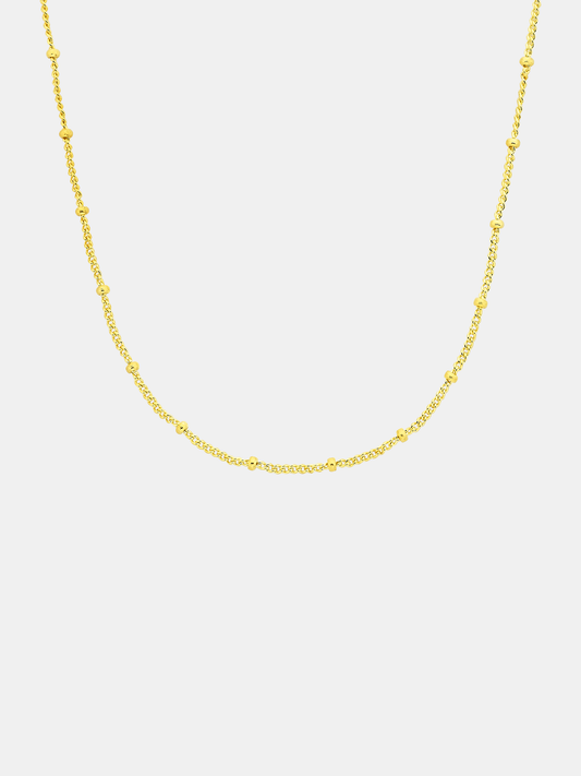 Gold chain necklace on a light gray background