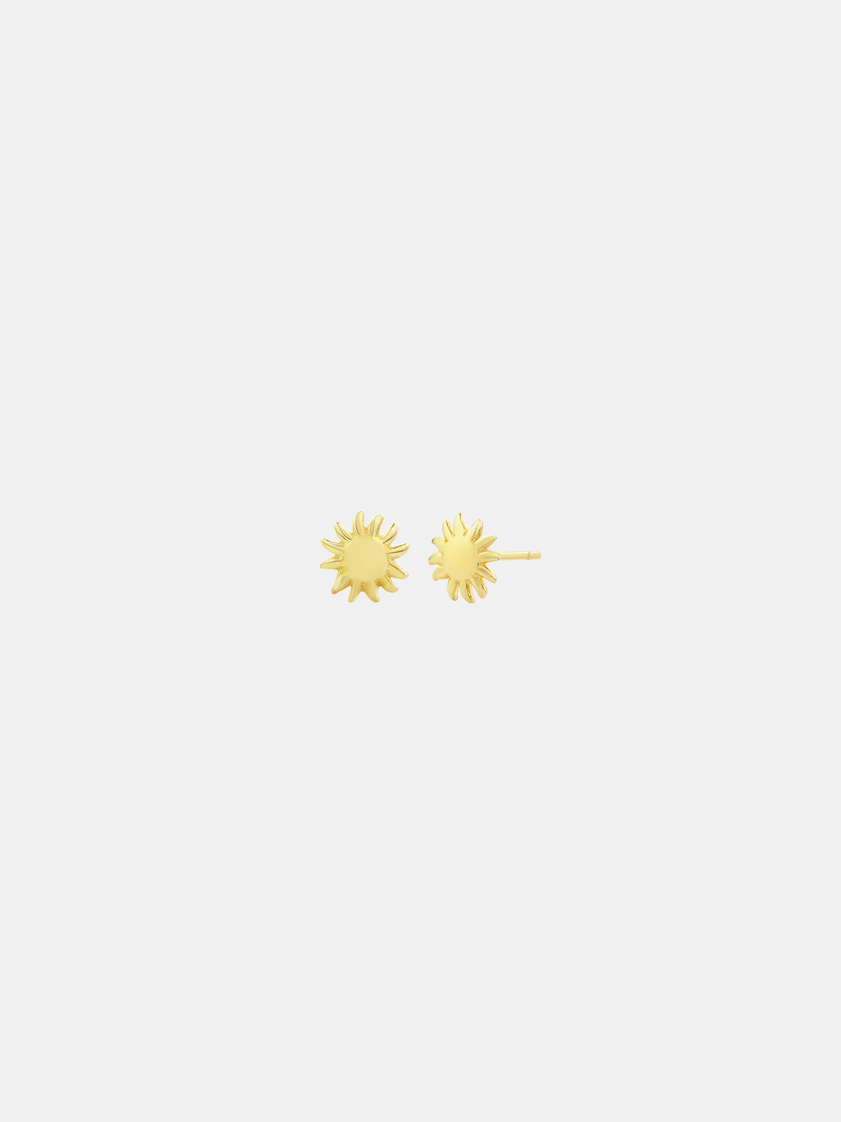 Gold sun-shaped earrings on a light gray background