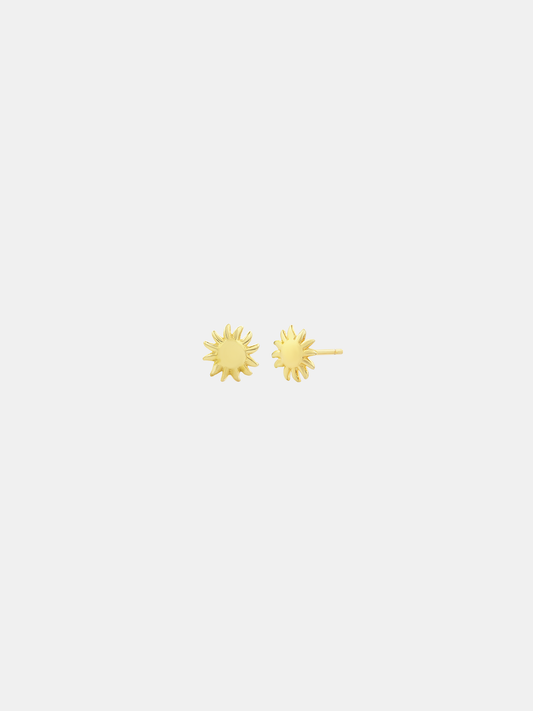 Gold sun-shaped earrings on a light gray background