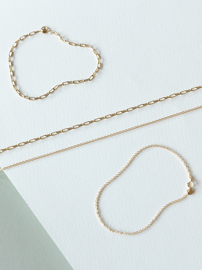 Solid gold necklaces & bracelets - mini links & cable chains on a light background