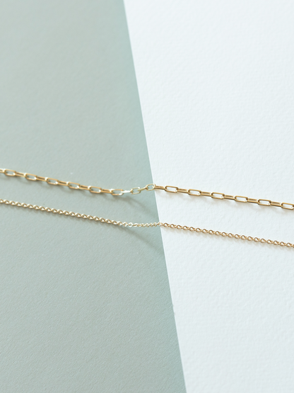 Mini links (top) and cable (bottom) chains on a light green and white background