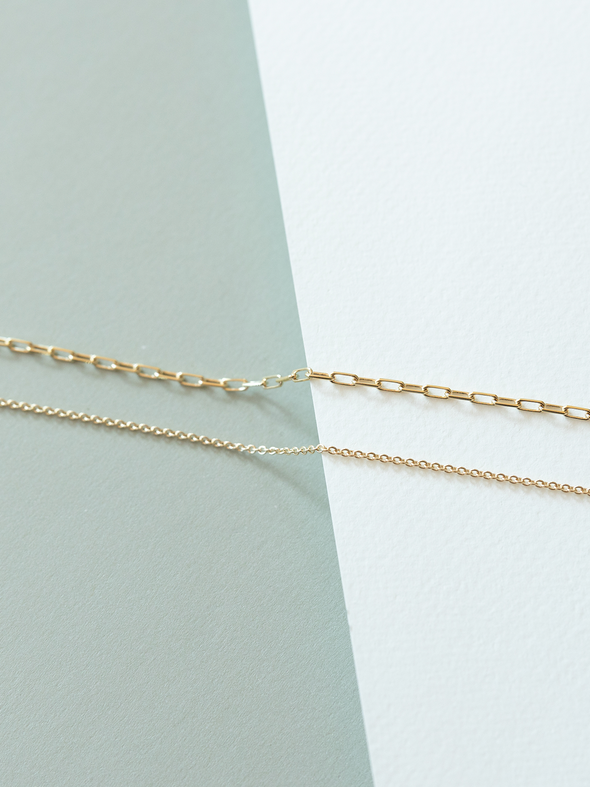 Mini links (top) and cable (bottom) chains on a light green and white background