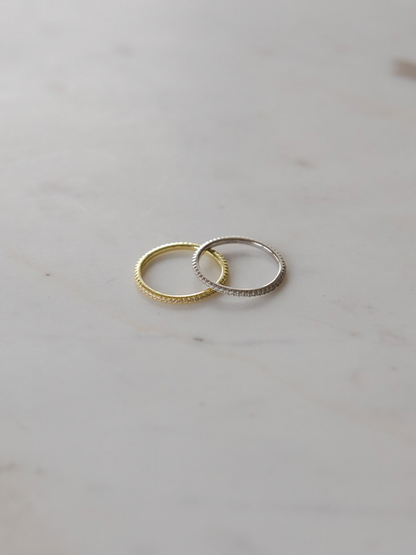 Two rings, one gold and one silver, on a light gray surface.