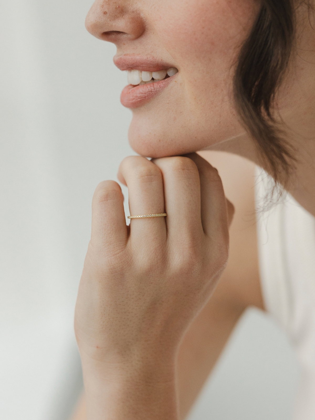 Close-up of a person wearing a gold ring on a neutral background