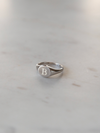 Silver signet ring engraved with a B on a light gray background