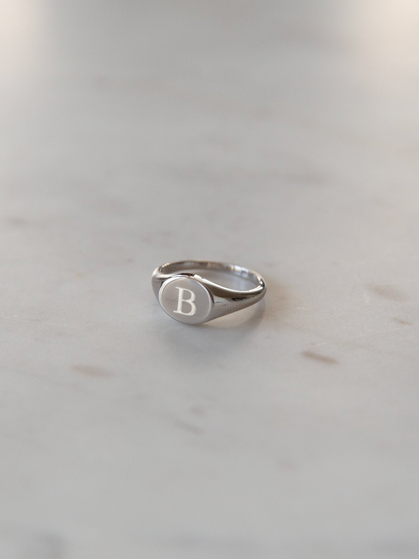 Silver signet ring engraved with a B on a light gray background