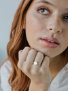 Woman wearing a signet ring, looking thoughtfully.