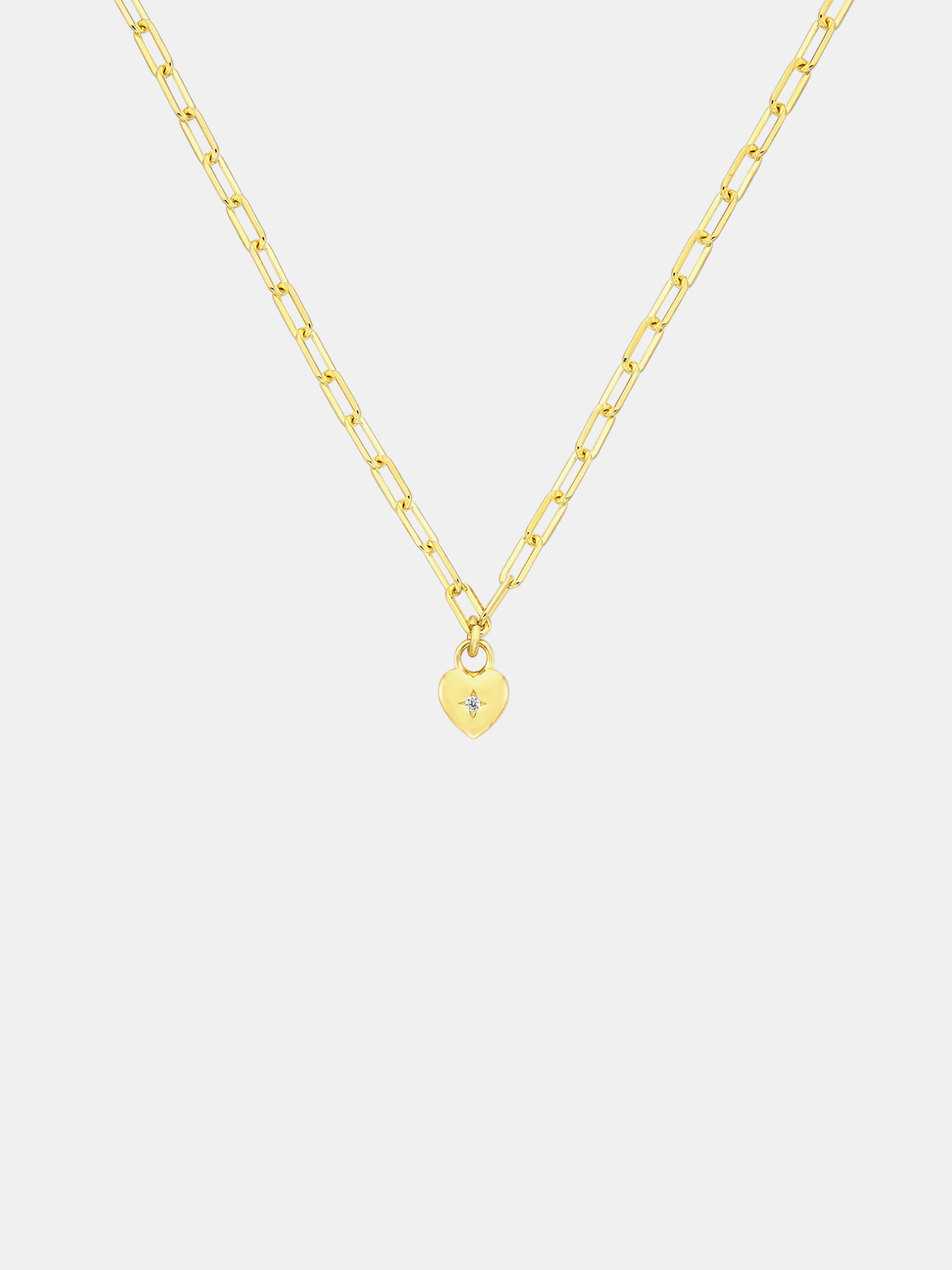 Gold necklace with a small sweetheart pendant on a light gray background