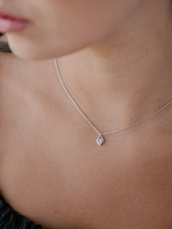 Silver necklace with a heart pendant on a person's neck