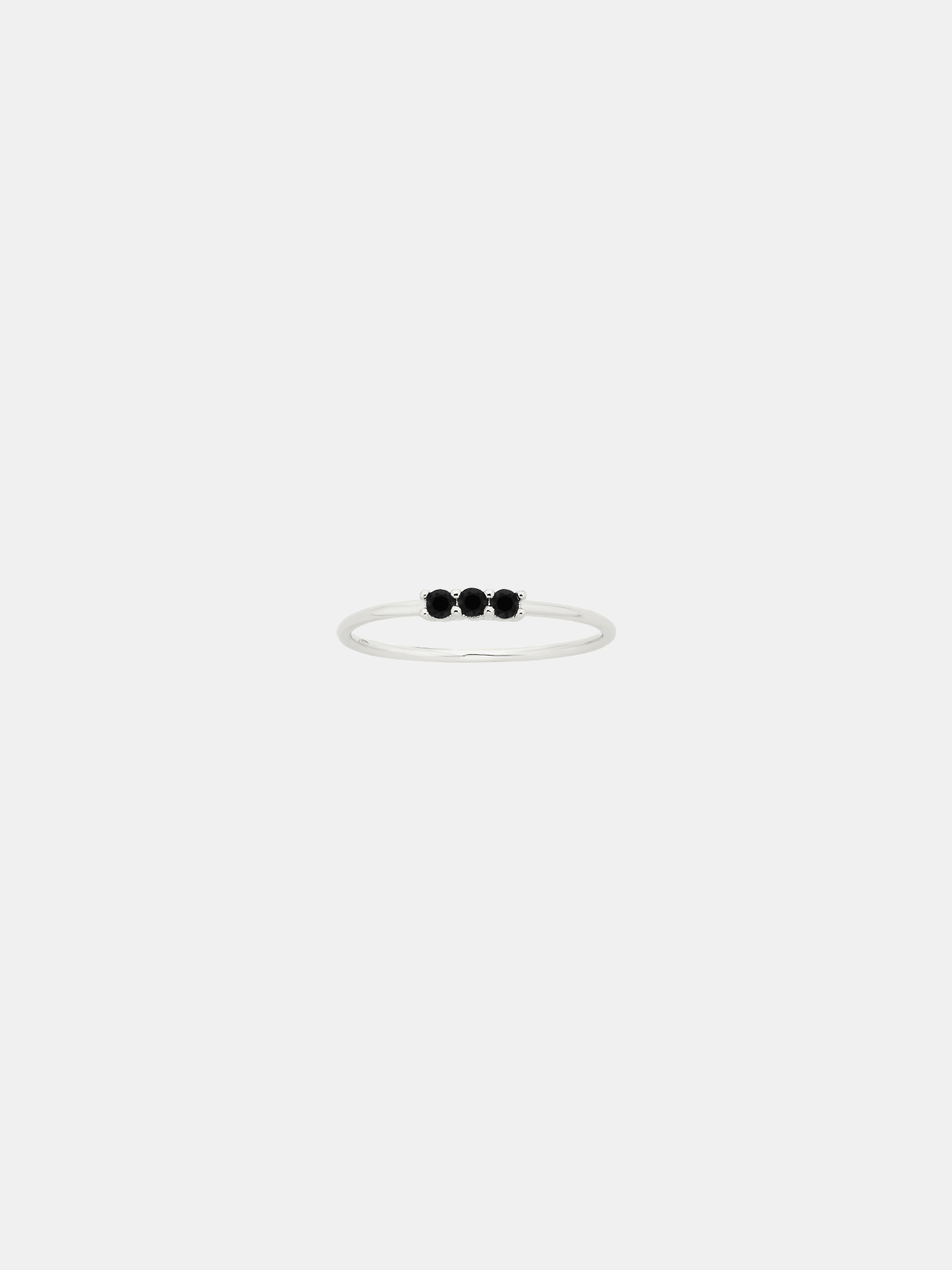 Thin silver ring with three black stones on a white background