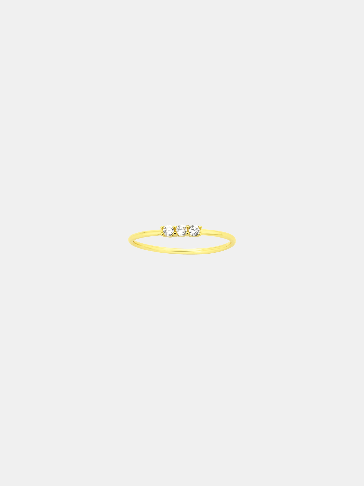Gold ring with three stones on a light beige background
