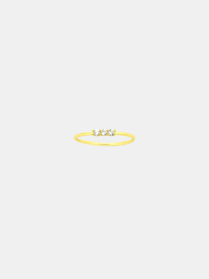 Gold ring with three stones on a light beige background