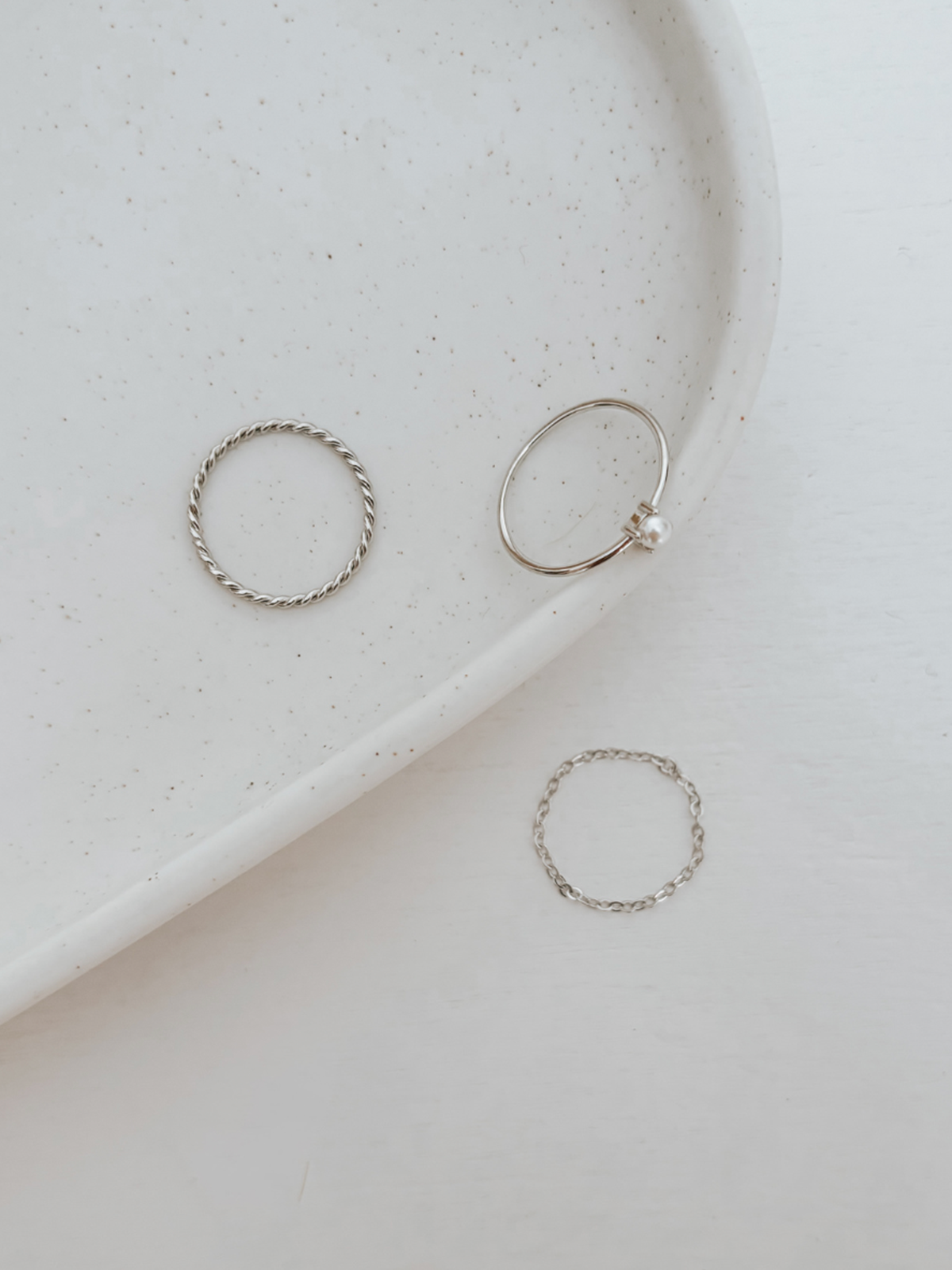 Three silver rings on a white speckled plate