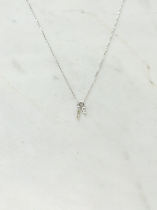 Silver necklace with a small birthstone & letter pendant on a marble surface