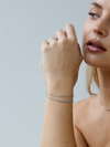Woman wearing a silver bracelet on a plain background