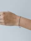 Silver bracelet on a wrist against a light gray background