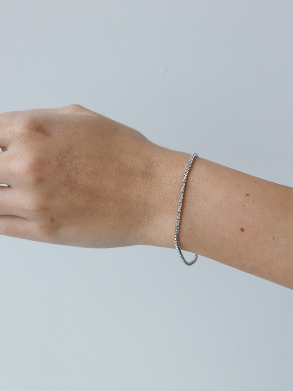 Silver bracelet on a wrist against a light gray background